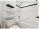 Bright bathroom features a shower-over-tub and shelving with towels and black linens at 223 Cadiz Loop, Davenport, FL 33837