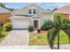 Charming two-story home featuring a brick driveway, manicured landscaping, and an attached garage at 223 Cadiz Loop, Davenport, FL 33837
