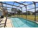An inviting screened-in pool with a clear view of the surrounding backyard and community at 223 Cadiz Loop, Davenport, FL 33837