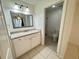 Bathroom with granite vanity top, decorative mirror, and tiled floors, with view into adjacent shower room at 2330 Prime Cir # A, Kissimmee, FL 34746