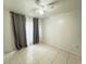 An airy bedroom with a ceiling fan, tile flooring, and window with light and dark curtains at 2330 Prime Cir # A, Kissimmee, FL 34746