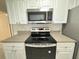 Close up of black stovetop and stainless steel microwave in a white kitchen at 2330 Prime Cir # A, Kissimmee, FL 34746