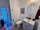 Well-lit half bathroom with gray vanity and sink, toilet, and modern fixtures near exterior exit at 2691 Cypress Tree Trl, St Cloud, FL 34772