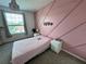 Cozy bedroom featuring a pink accent wall, ample natural light, and comfortable furnishings at 2691 Cypress Tree Trl, St Cloud, FL 34772