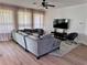 Spacious living room with sleek hardwood floors, modern gray sofa, sheer curtains and a ceiling fan at 2691 Cypress Tree Trl, St Cloud, FL 34772