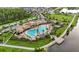 Stunning aerial view of the community clubhouse with a large pool, surrounded by lush landscaping and a serene lake at 2702 Giardino Loop, Kissimmee, FL 34741