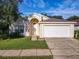 Attractive single-story home showcasing a well-manicured lawn, attached garage and arched front entrance at 421 Bailey Cir, Davenport, FL 33897
