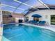 Inviting screened-in pool area with lounge chairs, dining set, grill and clear, refreshing water at 421 Bailey Cir, Davenport, FL 33897