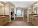 Bright bathroom features a tub beneath a large window, a glass shower, and separate sink vanities at 4301 Mohawk Ct, St Cloud, FL 34772