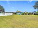 Large grassy backyard with a white picket fence, surrounding mature trees, and several colorful houses in the distance at 4413 Chalfont Dr, Orlando, FL 32837