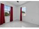 Bright bedroom features tile floors and natural light from two windows with dark red curtains at 491 Majestic Gardens Blvd, Winter Haven, FL 33880
