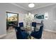 Elegant dining area with a glass table, plush blue chairs, and sliding glass doors at 5253 Pebble Beach Blvd, Winter Haven, FL 33884