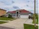 Single Gathering home features a red roof, attached garage, and lush green lawn at 5418 Crepe Myrtle Cir, Kissimmee, FL 34758
