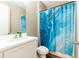 Well-lit bathroom with a modern vanity, toilet, and a shower-tub combination with a blue patterned shower curtain at 5876 Bar Ranch Rd, St Cloud, FL 34771