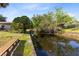 A picturesque canal in a green backyard with a wooden bench under a bright blue sky at 106 Edgewater Dr, St Cloud, FL 34769