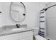 Bathroom with granite countertop, a round mirror and a shower featuring a blue and white shower curtain at 106 Edgewater Dr, St Cloud, FL 34769