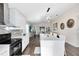 Modern kitchen with white cabinets, black appliances, and an island with barstool seating open to living room at 106 Edgewater Dr, St Cloud, FL 34769