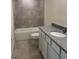 This bathroom features a shower-tub combo, grey tile, and a vanity with a granite countertop at 1148 Sugarwood St, Davenport, FL 33837