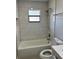 Bathroom with white tub, marble tile surround and modern fixtures with a window for natural light at 1256 S Bumby Ave, Orlando, FL 32806
