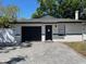 Inviting single-story home featuring a dark garage door, brick details and a new white perimeter fence at 1256 S Bumby Ave, Orlando, FL 32806
