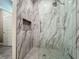 Tiled shower with a glass door and niche, featuring marble-look walls and a mosaic-tiled shower floor at 1373 Williams Rd, Winter Garden, FL 34787