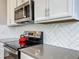 Close up of the kitchen with white cabinets, gray counters, stainless appliances and a red tea kettle on the stove at 1373 Williams Rd, Winter Garden, FL 34787