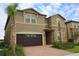 Two-story home with a brick driveway, attached garage, well-maintained landscaping, and inviting curb appeal at 2147 Tripoli Ct, Kissimmee, FL 34747