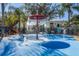 Community splash pad with vibrant blue base, overhead sprinkler, and playful water jets under a sunny sky surrounded by trees at 2322 Silver Palm Dr, Kissimmee, FL 34747