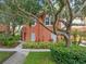 Charming two-story townhouse with a tiled roof, lush landscaping, and mature trees at 3015 Yellow Lantana Ln, Kissimmee, FL 34747