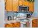 Efficient kitchen featuring a microwave, oven, white appliances, and plenty of counter space and wooden cabinets at 3015 Yellow Lantana Ln, Kissimmee, FL 34747