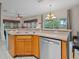 Functional kitchen area with modern stainless steel dishwasher and wooden cabinets, with a pass-through to living room at 3015 Yellow Lantana Ln, Kissimmee, FL 34747