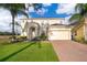 Two-story home featuring manicured lawn, palm trees, brick driveway, and a two-car garage at 389 Yellow Snapdragon Dr, Davenport, FL 33837