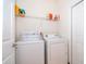 Efficient laundry room with white washer, dryer and overhead shelving for organized storage at 389 Yellow Snapdragon Dr, Davenport, FL 33837