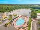 Aerial shot of a community pool with people swimming and lounging, set beside a lake with a fountain feature at 4551 Jonafree Ln # 103, Kissimmee, FL 34746