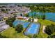 Aerial view of tennis and basketball courts near a lake, playground, and apartment homes in a vibrant community at 4551 Jonafree Ln # 103, Kissimmee, FL 34746