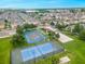 Aerial view of tennis and basketball courts in a community near townhomes, a pool, and a picturesque lake at 4551 Jonafree Ln # 103, Kissimmee, FL 34746