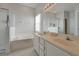 A bright bathroom features double sinks, large tub, glass enclosed shower, and white tile floors at 553 Bailey Cir, Davenport, FL 33897