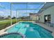 Private screened-in pool area with a spa, lounge chairs, and a peaceful backyard at 553 Bailey Cir, Davenport, FL 33897