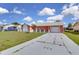 Inviting front exterior with an expansive driveway, garage, and well-kept lawn at 572 Floral Dr, Kissimmee, FL 34743