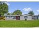 Charming single-story home with a red front door, blue shutters, and a well-maintained lawn at 6824 Chaucer Ln, Orlando, FL 32809