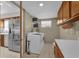 Functional laundry room featuring a washer, dryer, shelving, and storage with an adjacent view into the kitchen at 6824 Chaucer Ln, Orlando, FL 32809
