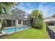 This property has a screened-in pool surrounded by a well-maintained backyard with tropical plants and green grass at 7745 Comrow St, Kissimmee, FL 34747