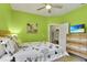 Vibrant green bedroom with light wood floors, a ceiling fan, natural light, and ensuite bath at 7745 Comrow St, Kissimmee, FL 34747