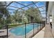 View of screened-in pool and spa with surrounding trees and lush landscaping at 7745 Comrow St, Kissimmee, FL 34747