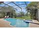 Screened-in pool and spa with lush landscaping and shaded seating at 7745 Comrow St, Kissimmee, FL 34747