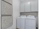 Laundry room with white washer and dryer units, white cabinets and geometric artwork at 811 Lake Dell Rd, Dundee, FL 33838