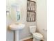 Elegant half bath featuring a pedestal sink, modern toilet and unique wall decor at 819 Lake Dell Rd, Dundee, FL 33838
