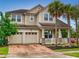 Charming two-story home featuring a brick driveway, two-car garage, and a welcoming front porch framed by columns and palm trees at 8635 Tallfield Ave, Orlando, FL 32832