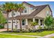 Charming two-story home with palm trees and a covered porch with stone accents and a two car garage at 8635 Tallfield Ave, Orlando, FL 32832