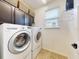 Bright laundry room features front load washer and dryer, overhead cabinetry and a storage rack at 8635 Tallfield Ave, Orlando, FL 32832